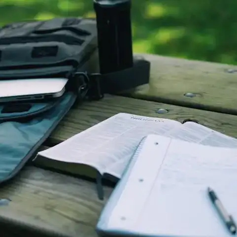 Image d'un sac à dossur une table avec un ordinateur et un cahier. Photo par Aaron Burden pour Unsplash.