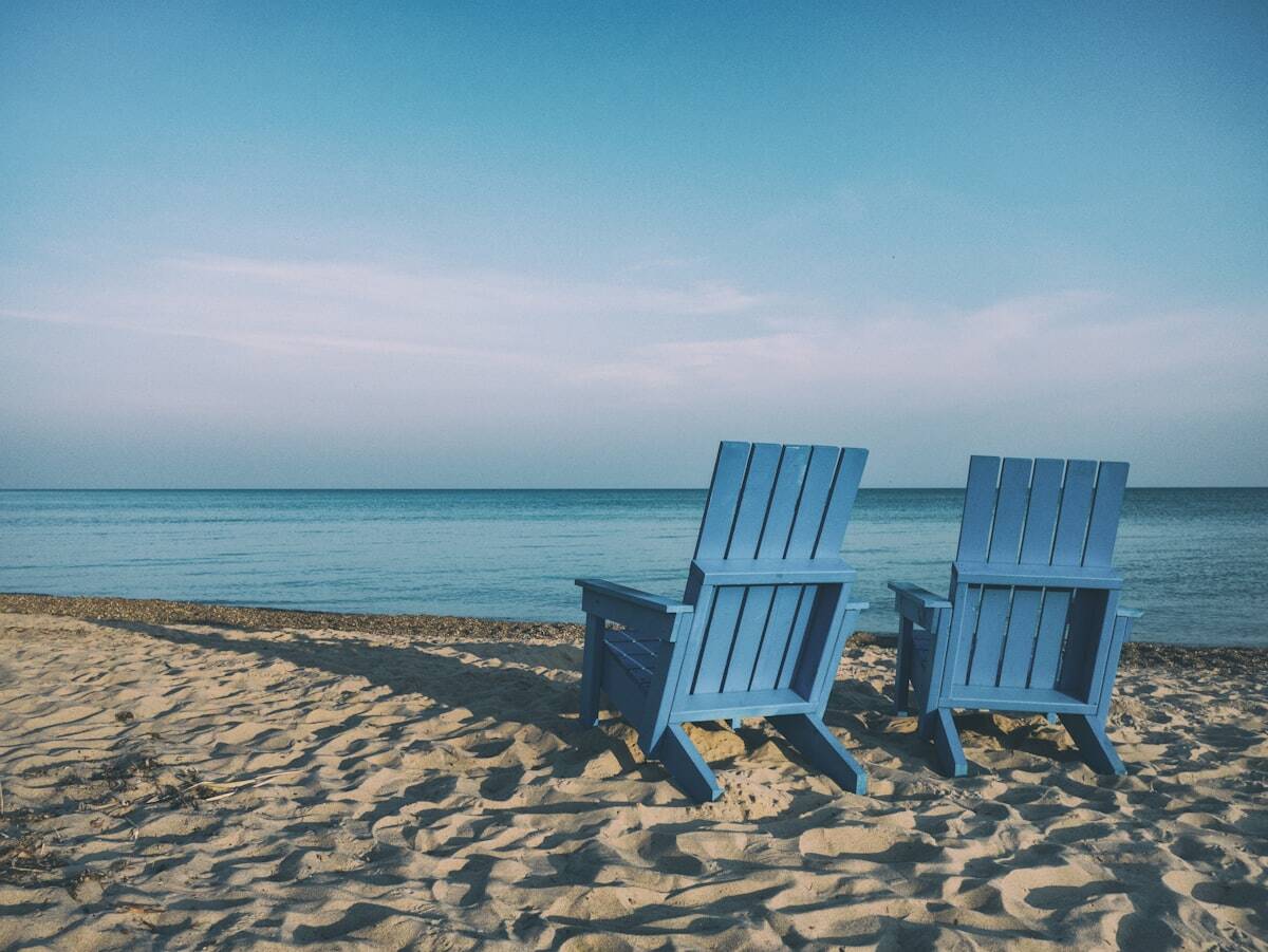 Deux chaises bleues sur une plage face à l'océan.